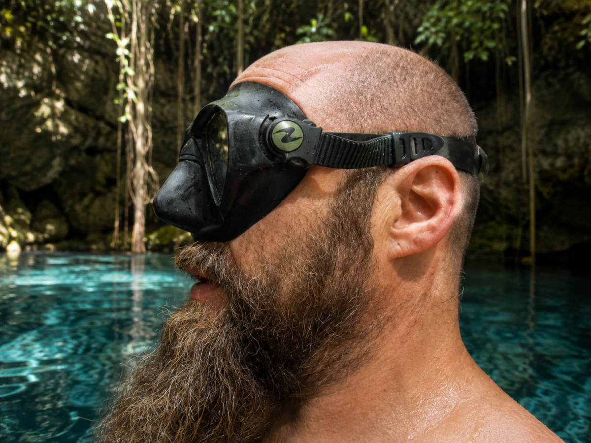 Side view of a diver wearing a scuba mask with the strap positioned just above the ears around the back of the head