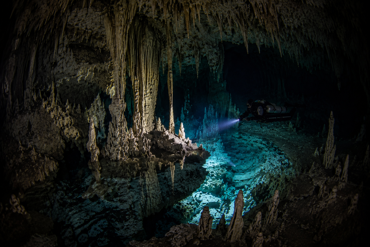 Cave diver exploring massive formations inside Dreamgate Cenote near Tulum Mexico